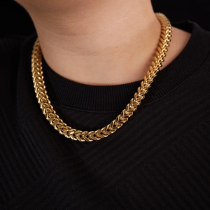 Men's gold stainless steel wheat chain necklace styled on a black ribbed shirt