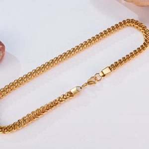 Polished gold Cuban link chain necklace for men in stainless steel on white background