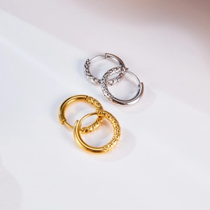 Detalle de pendientes de aro de acero inoxidable oro y plata con diseño martillado único