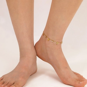 Close-up of golden tree of life anklet with sparkling zircon crystals on model foot