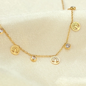 Detail of gold tree of life anklet with sparkling zircon stones on luxury silk