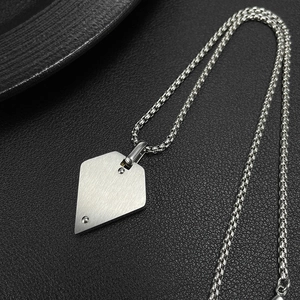 Detail of brushed silver shield pendant with metal rivets on a thick link chain