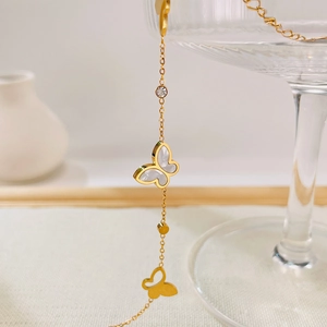 Dettaglio di una collana a farfalla dorata con inserto in madreperla bianca e zirconi