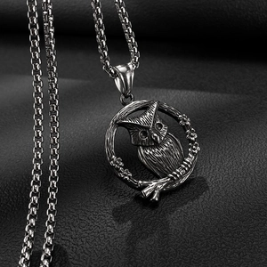 Gedetailleerde close-up van een vintage uilhanger met fijn graveerwerk en schakelketting