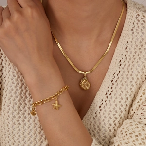 Dettaglio della collana con ciondolo a conchiglia dorata e bracciale a stella marina su modella