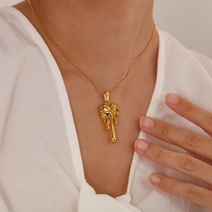 Collier avec pendentif cœur de lave doré porté par un mannequin sur chemise blanche