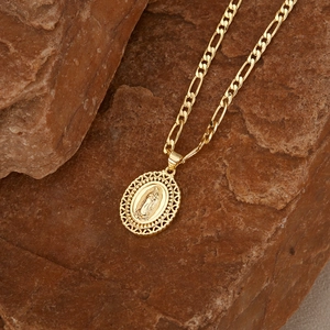 Detail van de gouden Maagd Maria hanger op natuursteen met Figaro-stijl ketting