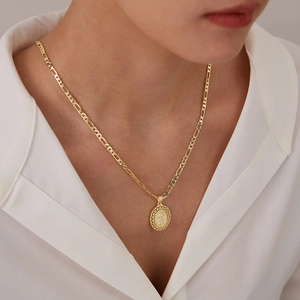 Detailopname van gouden Figaro-ketting met een Maagd Maria-medaillon gedragen door een model