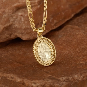 Macro-opname van de gouden Figaro-ketting met ovale filigraan hanger op getextureerde steen