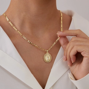 Gouden Maagd Maria hanger met Figaro-ketting gedragen door model in wit shirt