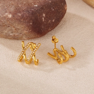 Detail of gold triple-claw crisscross earrings with cubic zirconia on stone base