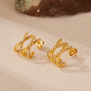 Close-up of triple-layer crossed J-shape gold stud earrings with cubic zirconia