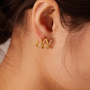 Macro shot of gold cross-line stud earrings with zircon inlay on model ear