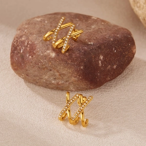 Macro shot of gold-plated titanium X-shape stud earrings with shimmering zircon stones