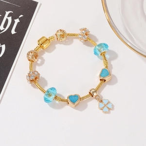 Dettaglio di bracciale a catena serpente dorato con ciondoli blu e quadrifoglio