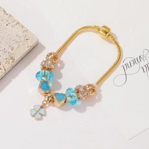 Dettaglio del bracciale con perline in oro rosa, cristalli blu e ciondolo a quadrifoglio