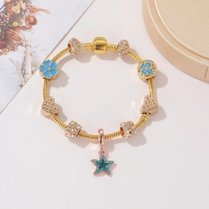 Dettaglio del bracciale a maglia serpente oro rosa con fiori blu e ciondolo a stella