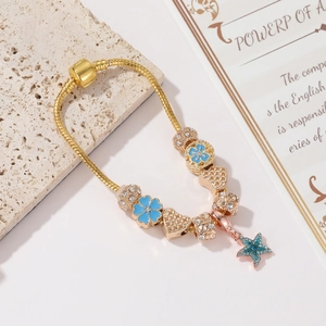 Dettaglio del bracciale con ciondoli oro rosa, fiori smaltati e pendente a stella marina