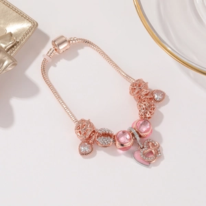 Dettaglio del bracciale mesh oro rosa con perle di cristallo rosa e ciondoli a cuore