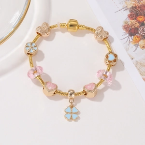 Dettaglio del bracciale a maglia snake oro rosa con perline smaltate e quadrifoglio