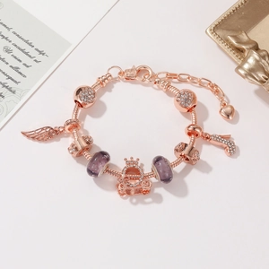 Dettaglio del bracciale con ciondoli in oro rosa, perle viola e pendente a forma di carrozza