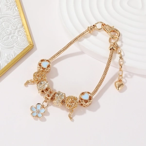 Macro shot of gold charm bracelet with light blue flower and musical note pendants