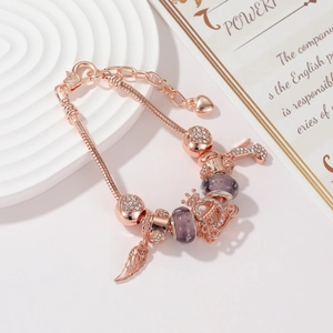 Dettaglio del bracciale a fiori oro rosa con perle di vetro viola e ciondolo corona