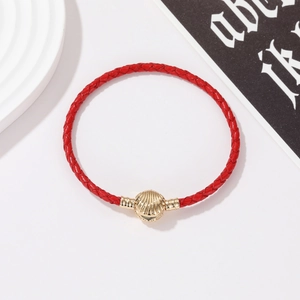 Detail van een rode gevlochten leren armband met een gouden metalen sluiting in schelpvorm