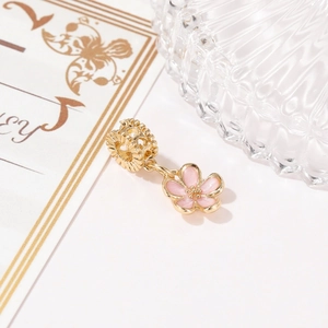 Macro detail of pink enamel cherry blossom pendant with golden flower charm beads