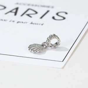 Detailed macro view of silver seashell pendant with braided ring on a display card