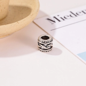 Detalle macro de una cuenta cilíndrica de plata antigua con textura de ondas para joyería DIY
