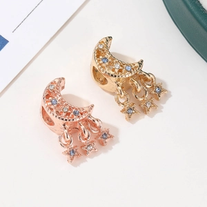 Detail eines mondförmigen Anhängers mit Hohlmustern und Sternanhängern in Goldtönen