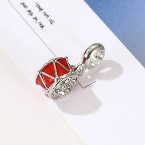 Macro view of a red enamel drum charm with sparkling crystal pavé and silver metal rim