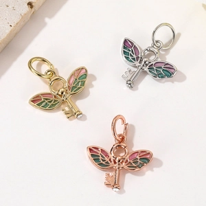 Close-up of three wing-key pendants in gold silver and rose gold with colorful enamel