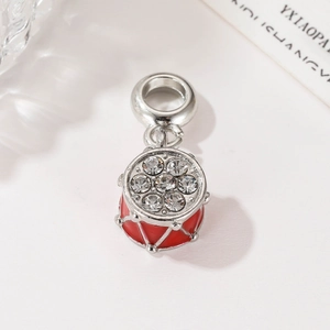 Exquisite drum charm pendant with red enamel and inlaid rhinestones on a white background