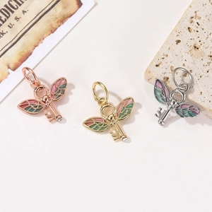 Macro shot of wing-shaped key pendants in rose gold, gold, and silver finishes