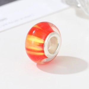Close-up of orange and yellow spiral resin charm bead with silver metal core insert