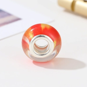 Detail of DIY jewelry bead with red and yellow swirl patterns and silver core