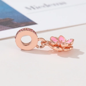 Macro shot of rose gold flower charm with pink enamel petals and inlaid zircon stones