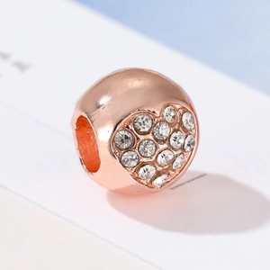 Makroaufnahme einer roségoldenen Herzperle mit weißen Kristallen für Armbänder