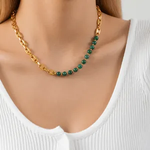 Detail of coffee bean link chain necklace with green beads worn on a model's neck