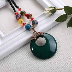 Macro di una collana vintage etnica con pendente ad anello verde scuro e perline colorate