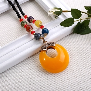 Dettaglio di una lunga collana bohémien con perline colorate e ciondolo a ciambella