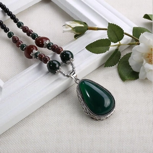 Détail du collier bohème avec pendentif goutte vert foncé et ciselure argentée fine