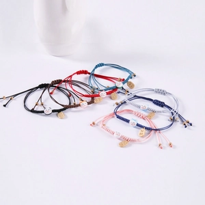 Dettaglio di bracciali intrecciati con gatti in ceramica e ciondoli portafortuna in metallo