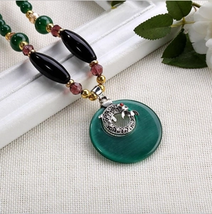 Détail du collier bohème avec perles, pendentif œil-de-chat vert et motif argenté ciselé