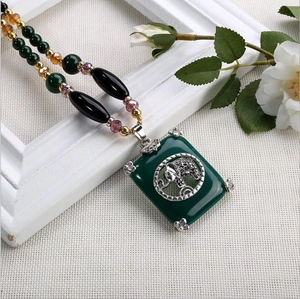 Détail du collier bohème avec pendentif en pierre verte et gravure d'éléphant argenté