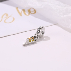 Macro shot of a silver lightning bolt charm with gradient yellow and orange zircons for bracelets