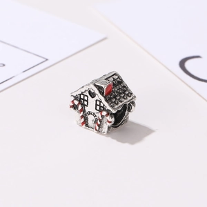 Macro shot of silver gingerbread house charm with festive candy canes and red chimney