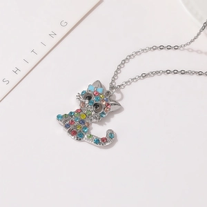 Dettaglio di una collana con ciondolo a gatto in argento con strass colorati e fiocco blu